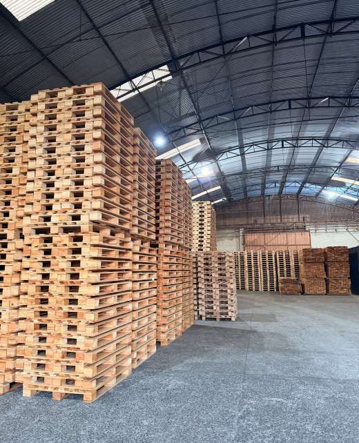Altas pilhas de pallets de madeira finalizados no galpão, garantindo grande capacidade de entrega para o seu orçamento de pallets